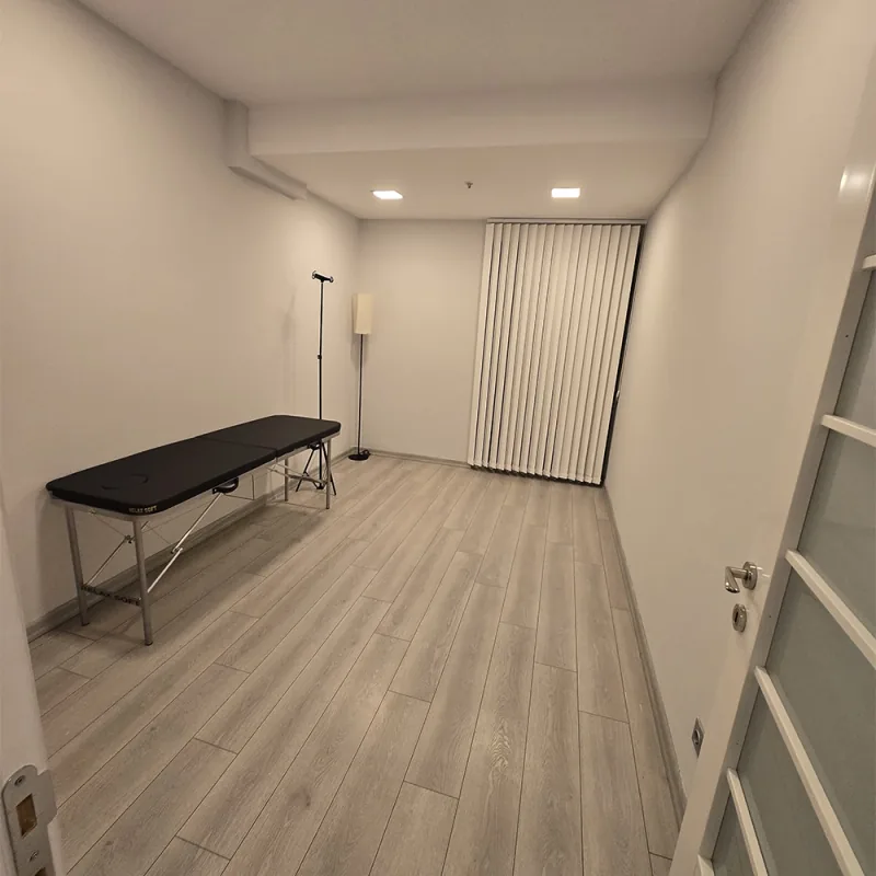 Raum mit einer schwarzen Untersuchungsliege und Vertikaljalousien